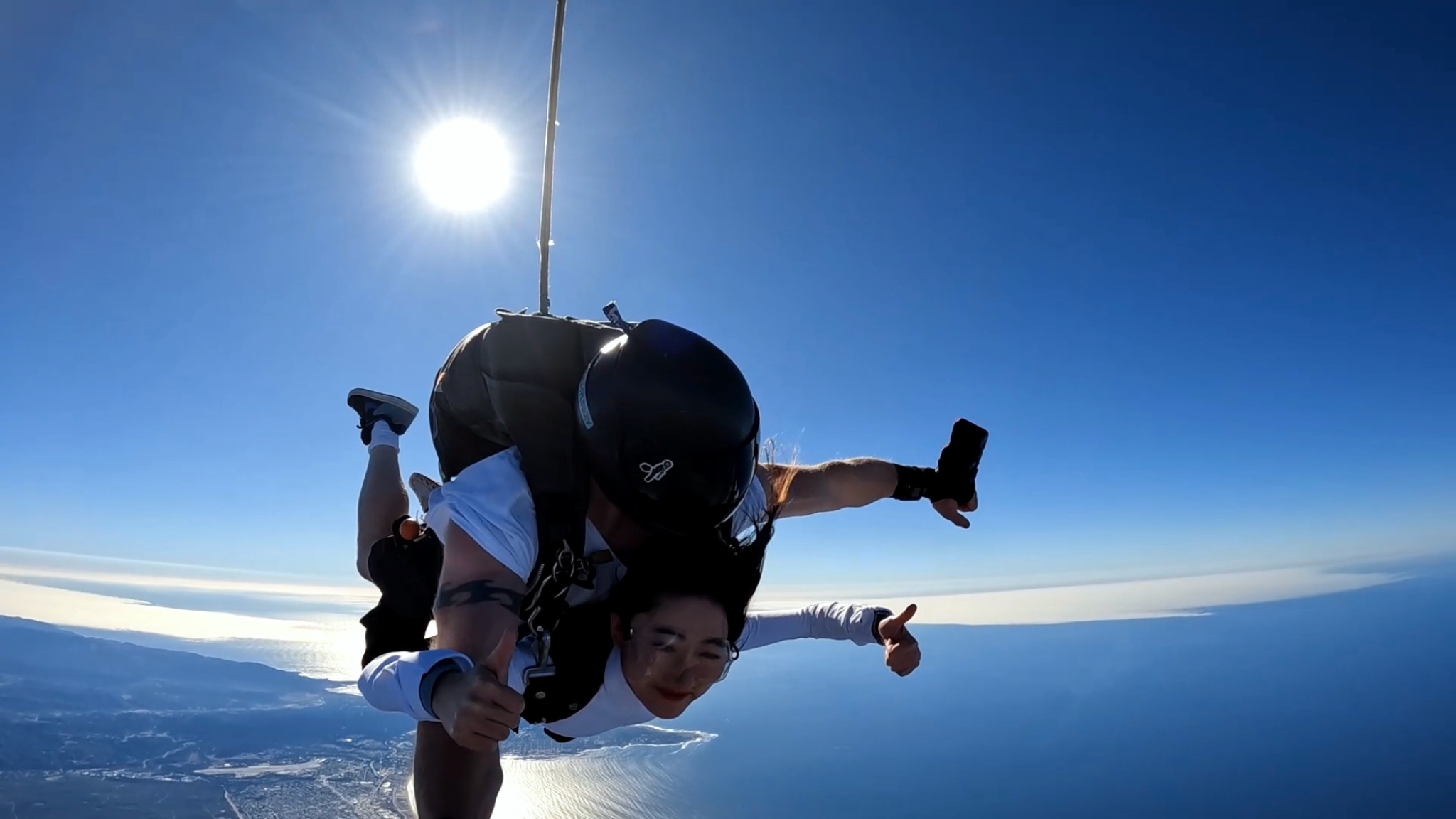 Tandem skydiving above a sunlit coastline