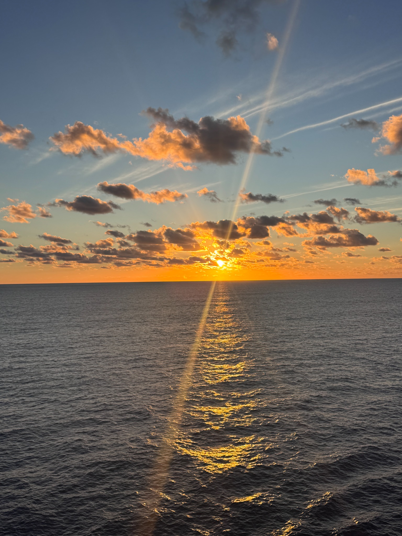Golden clouds and sunlight reflected across the sea at sunset